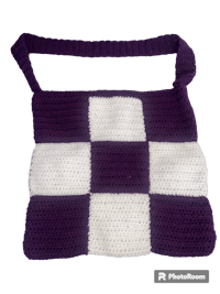 a purple and white crocheted bag on a black background